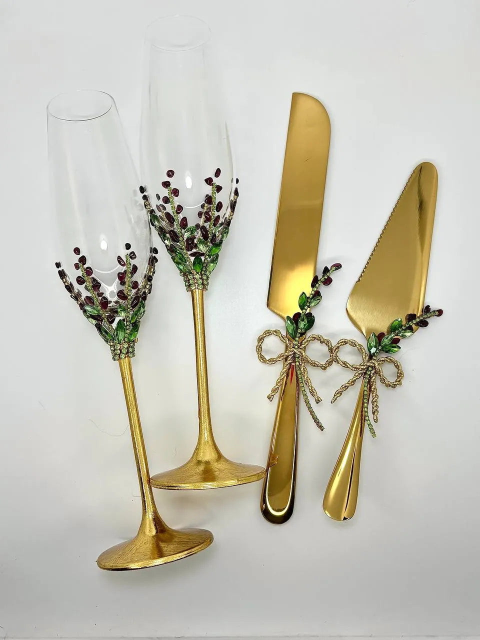 Personalized toasting glasses and gold cake knife adorned with garnet stones and floral elements