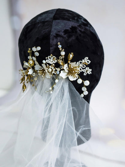 Close-up of gold flower hair pin with white floral details and pearls