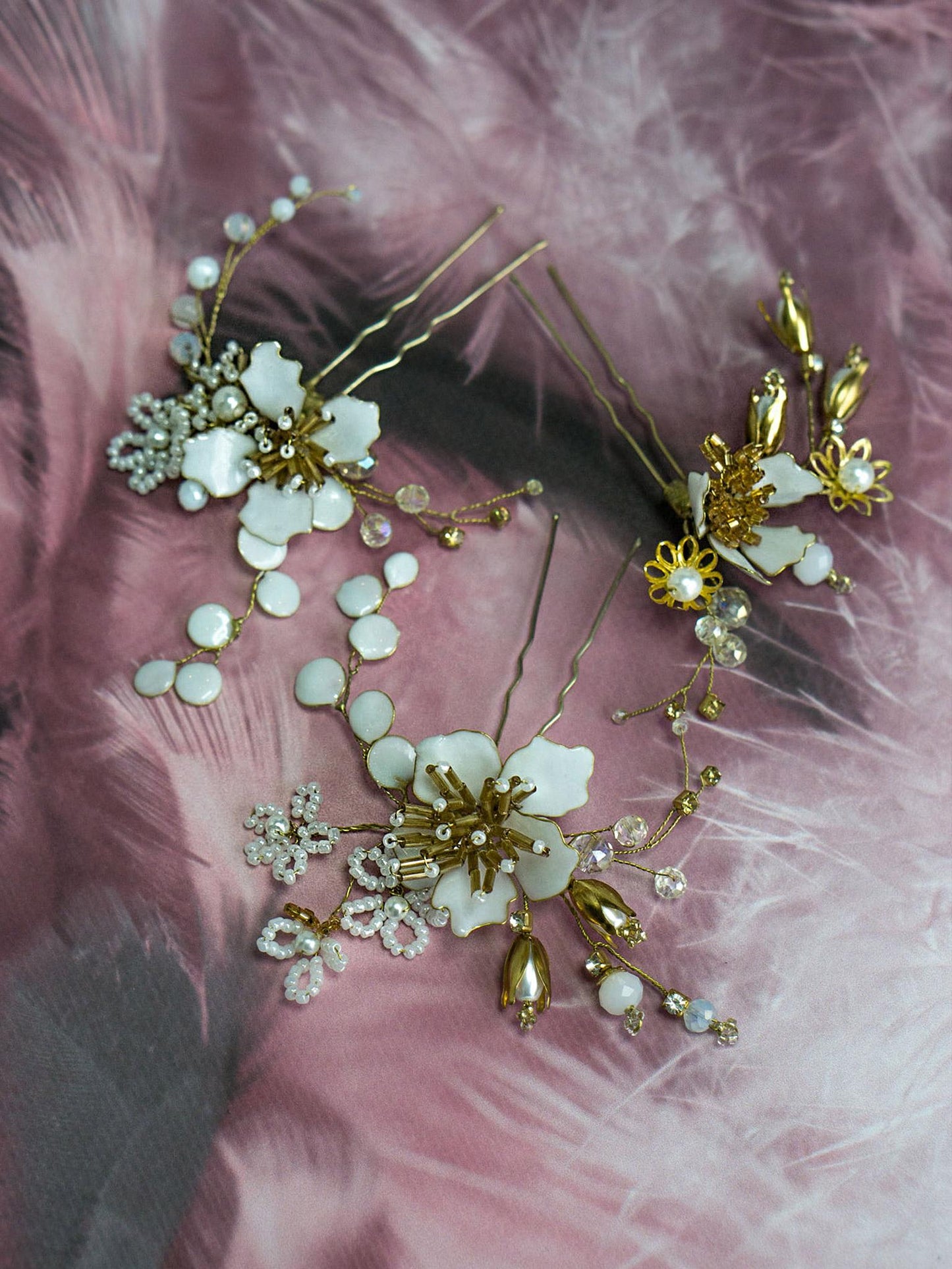 Three gold flower hair pins arranged on a white surface