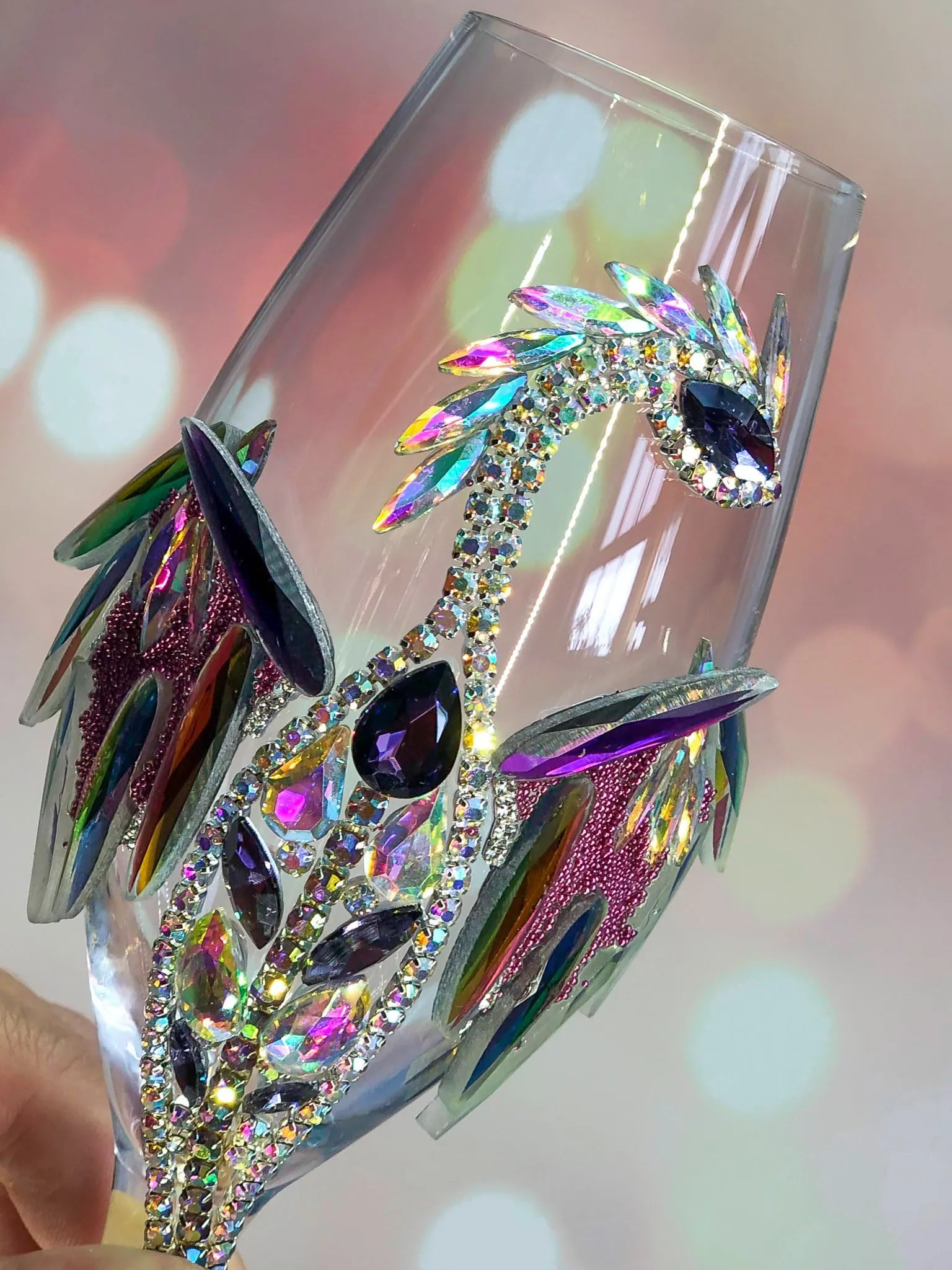 Close-up of a wineglass, highlighting intricate dragon designs studded with shimmering gemstones and a silver spiral stem.