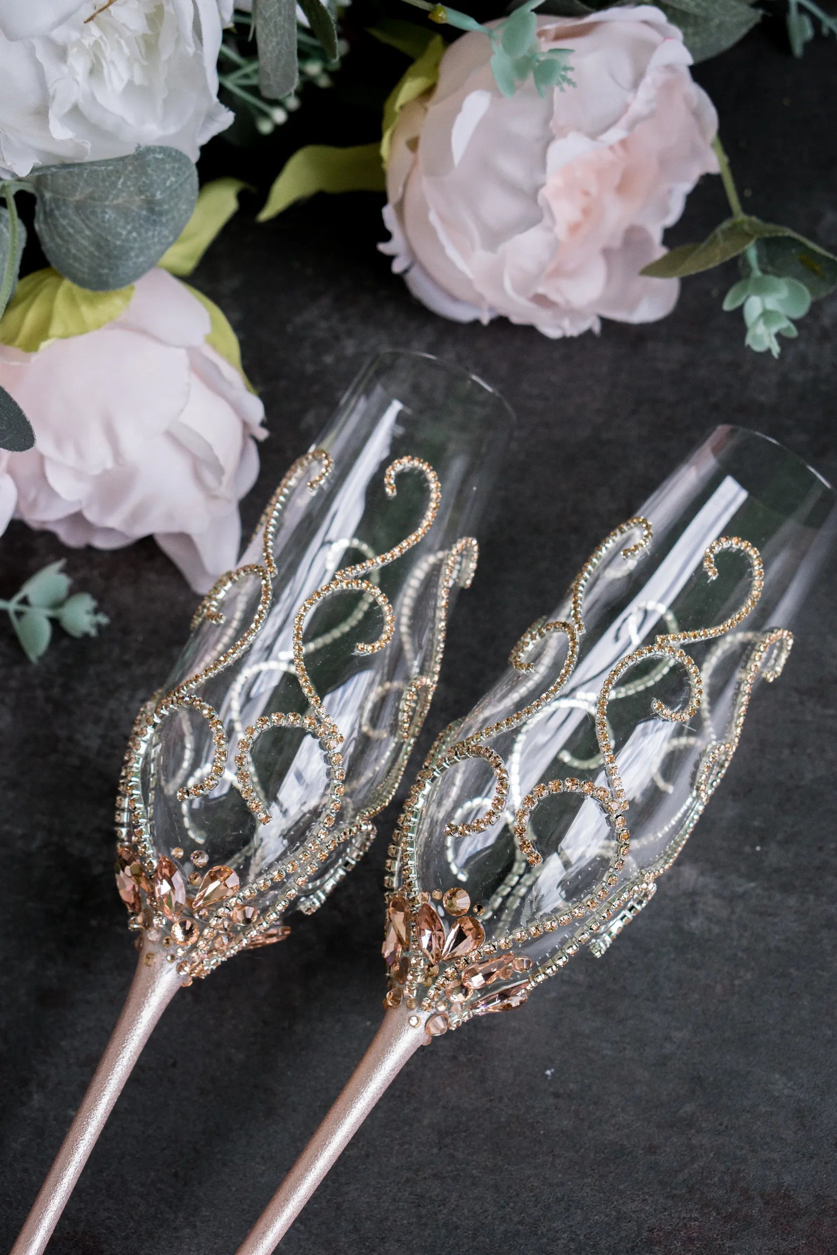 Handcrafted champagne flutes adorned with rose gold crystals for weddings