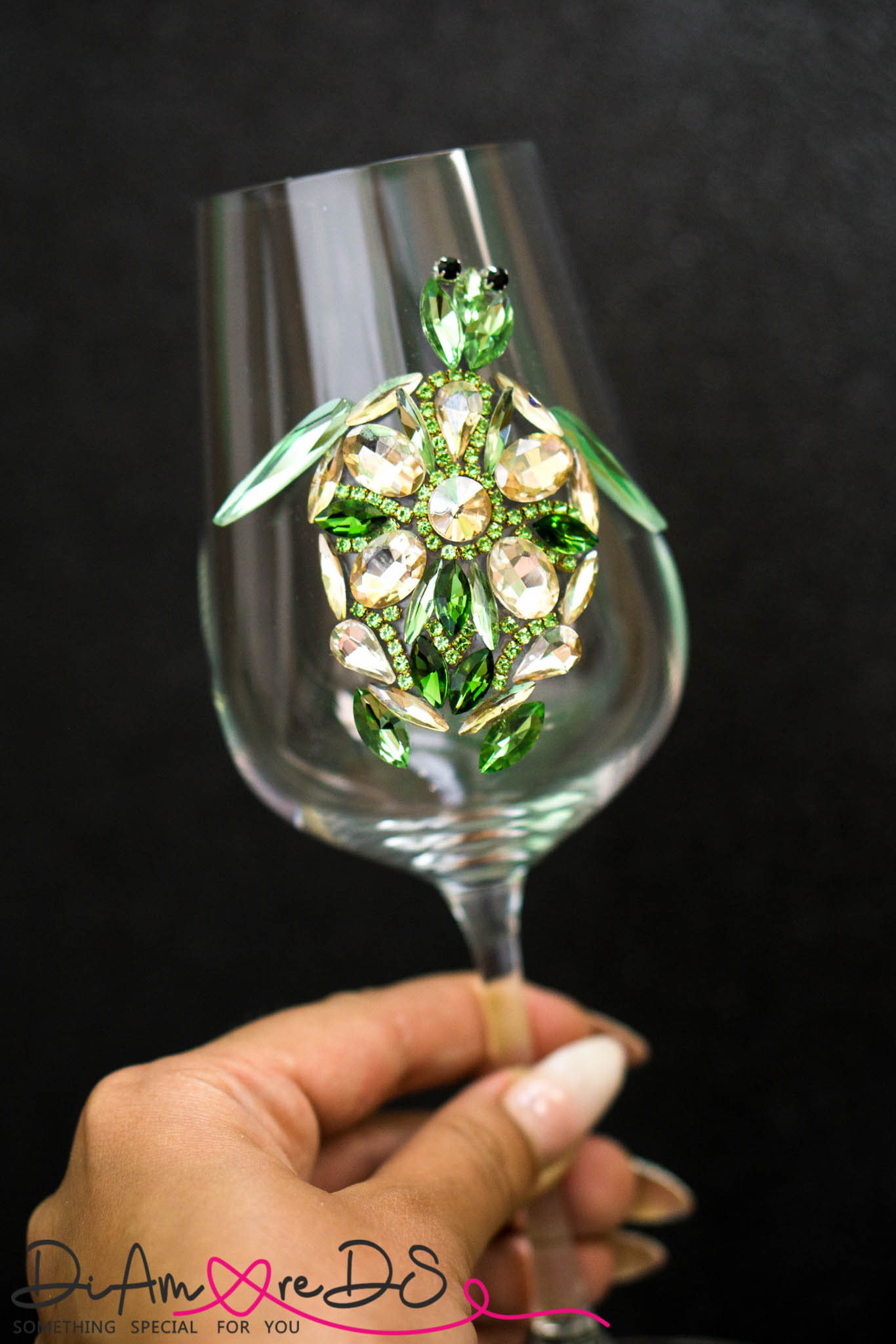 Close-up of a sea turtle-adorned wine glass stem, showcasing intricate crystal work against a dark backdrop.