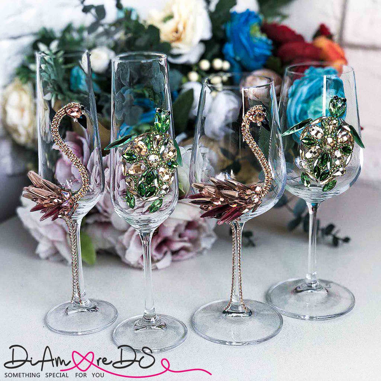 Assorted crystal champagne flutes with intricate flamingo and sea turtle jewel embellishments on a floral backdrop