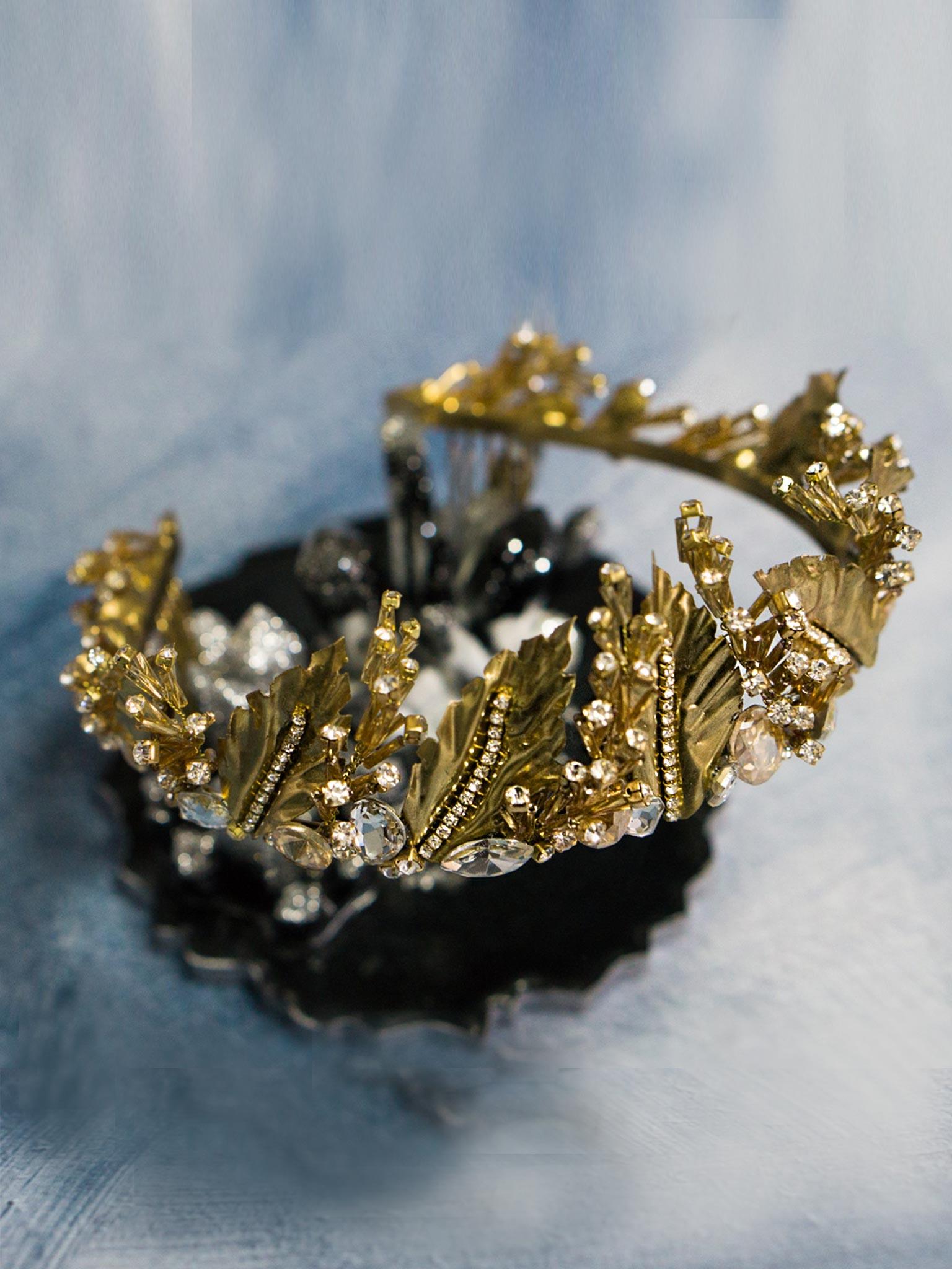 Close-up view of Gold Wedding Crown with Leaves and Crystals on blue background