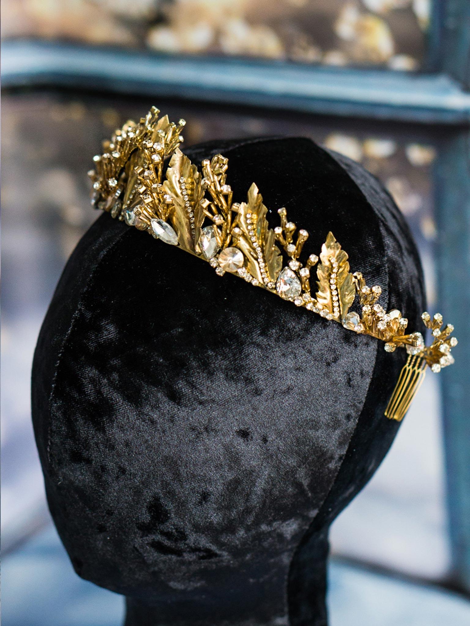 Gold wedding crown with leaves and crystals on black mannequin head